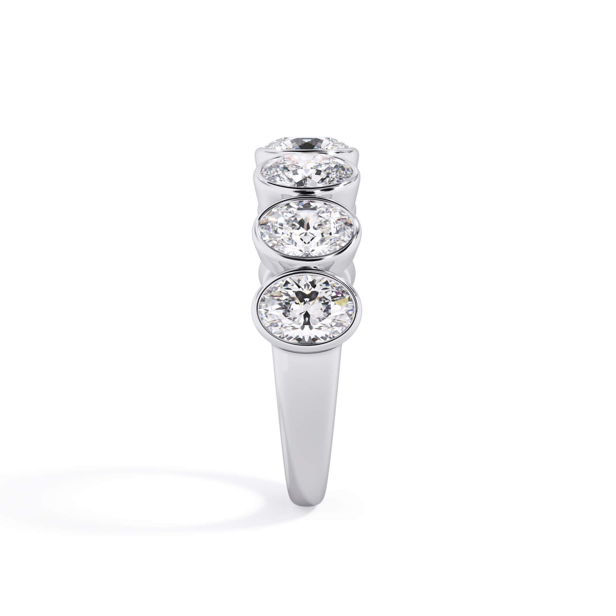 A picture of a seven stone diamond wedding ring with oval shaped diamonds that are bezel set in white gold or platinum on a white background with a side profile view.