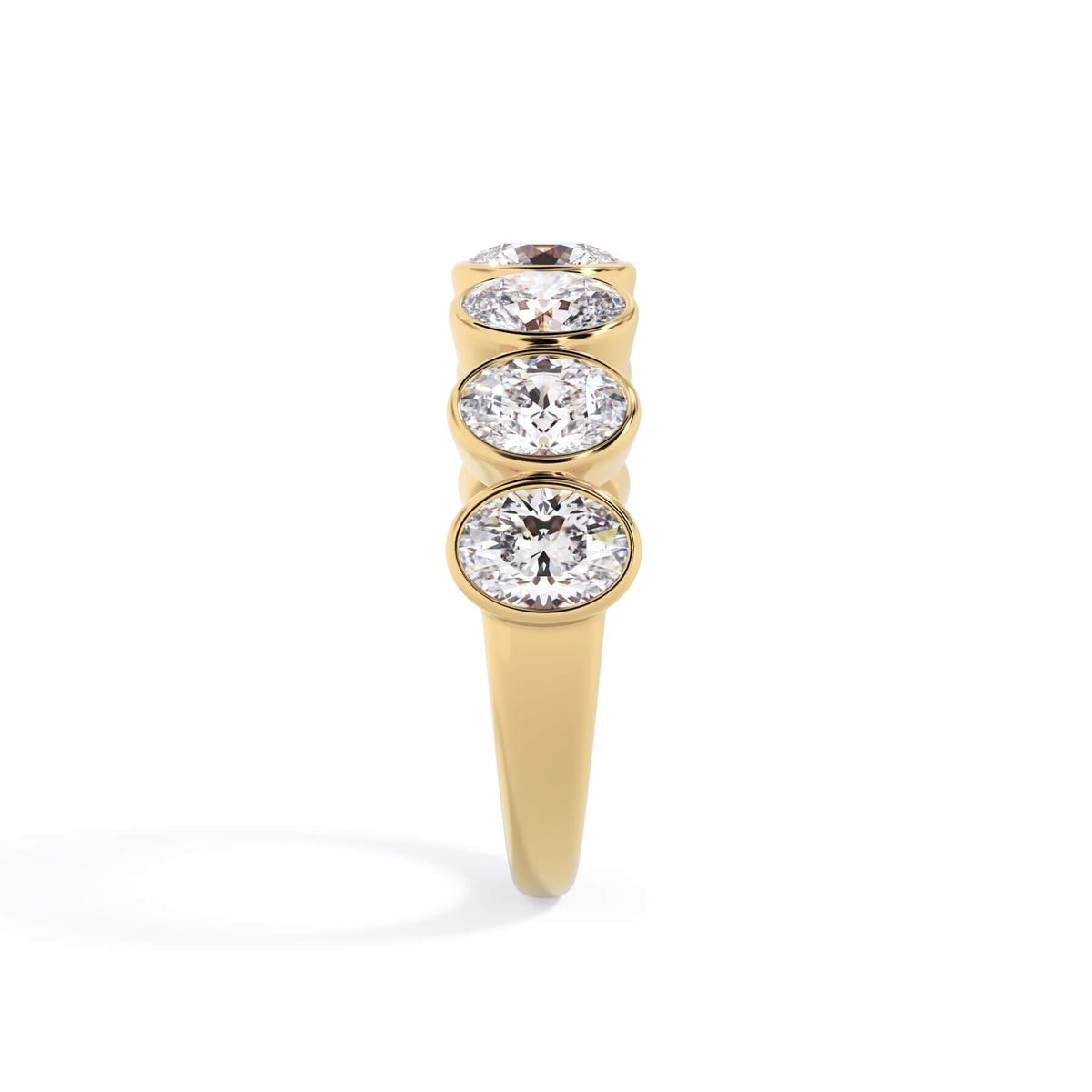 A picture of a seven stone diamond wedding ring with oval shaped diamonds that are bezel set in yellow gold on a white background with a side profile view.
