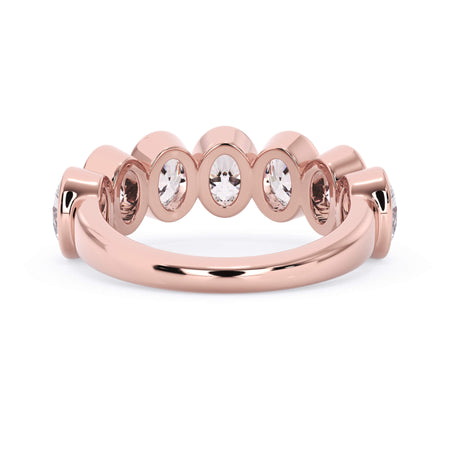 A picture of a seven stone diamond wedding ring with oval shaped diamonds that are bezel set in rose gold on a white background with a view of the underside of the ring.