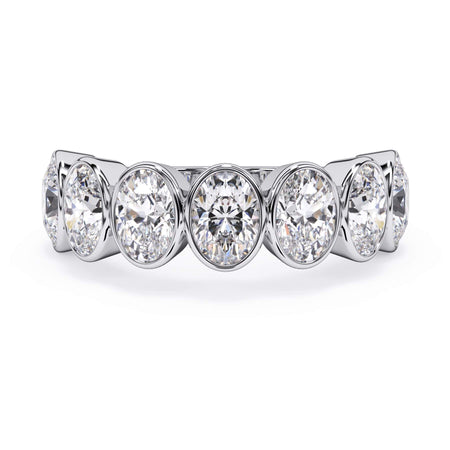 A picture of a seven stone diamond wedding ring with oval shaped diamonds that are bezel set in white gold or platinum on a white background with the ring facing forward, lying down.