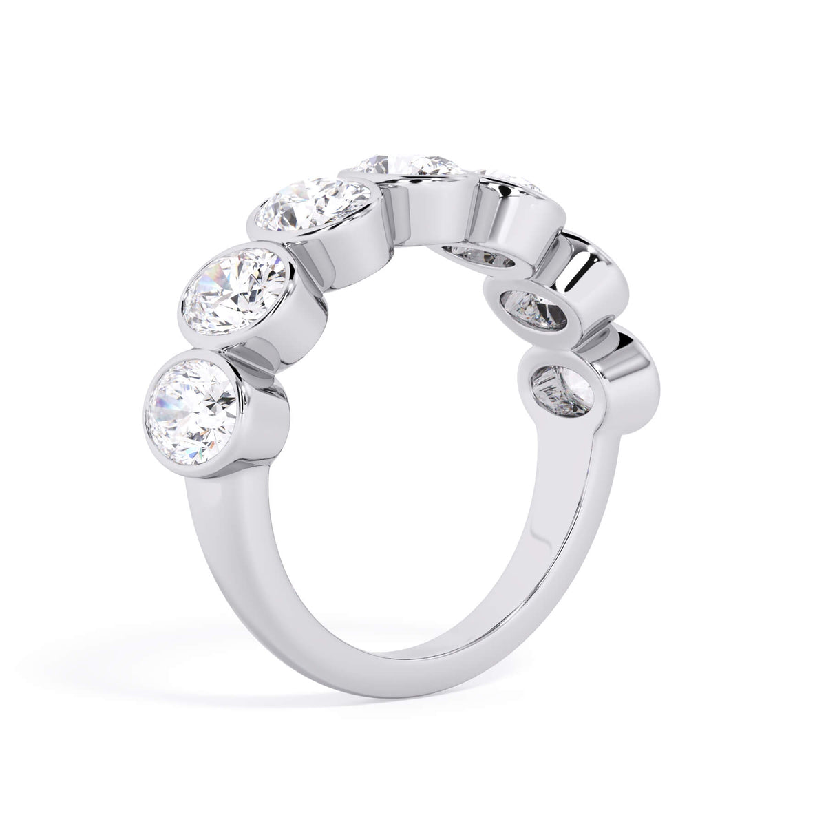 A picture of a seven stone diamond wedding ring with oval shaped diamonds that are bezel set in white gold or platinum on a white background with a slightly angled, through the finger view.