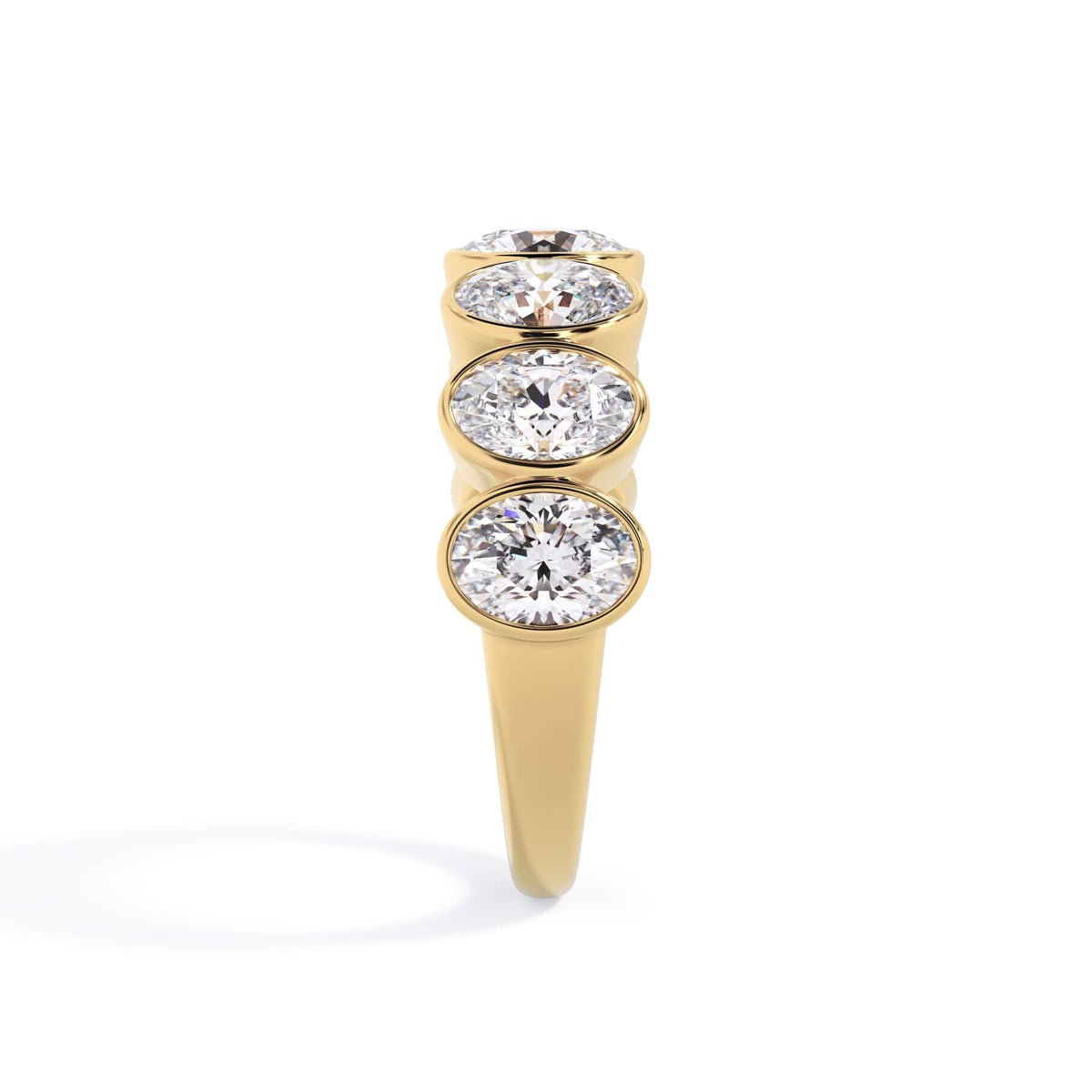A picture of a seven stone diamond wedding ring with oval shaped diamonds that are bezel set in yellow gold on a white background with a side profile view.