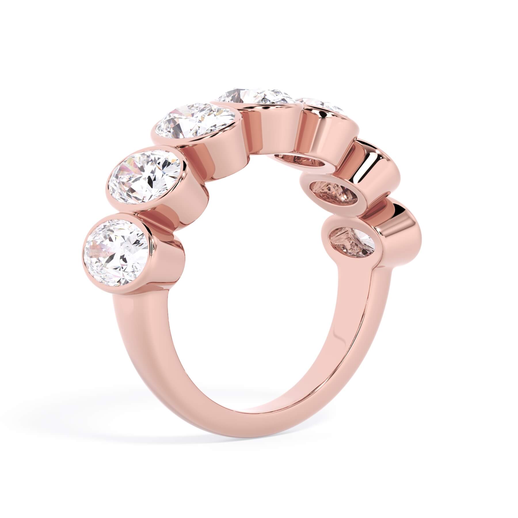 A picture of a seven stone diamond wedding ring with oval shaped diamonds that are bezel set in rose gold on a white background with a slightly angled, through the finger view.