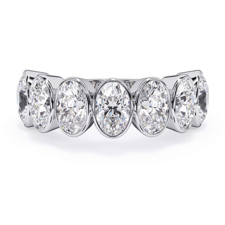 A picture of a seven stone diamond wedding ring with oval shaped diamonds that are bezel set in white gold or platinum on a white background with the ring facing forward, lying down.