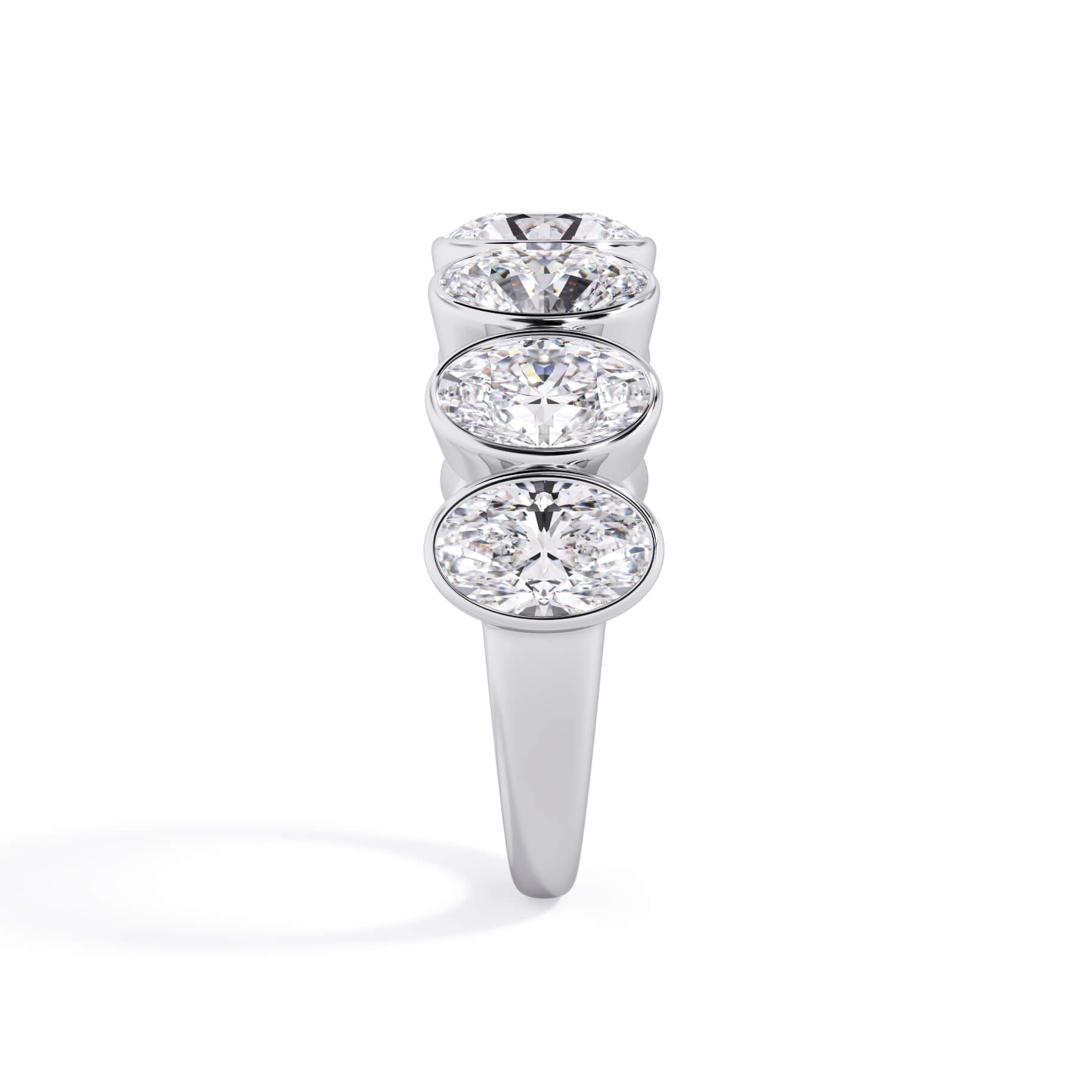 A picture of a seven stone diamond wedding ring with oval shaped diamonds that are bezel set in white gold or platinum on a white background with a side profile view.