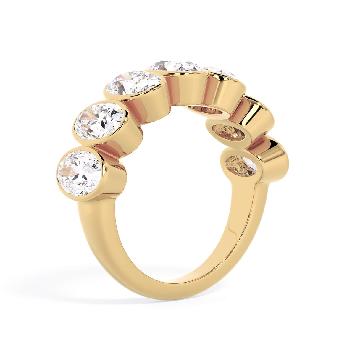 A picture of a seven stone diamond wedding ring with oval shaped diamonds that are bezel set in yellow gold on a white background with a slightly angled, through the finger view.