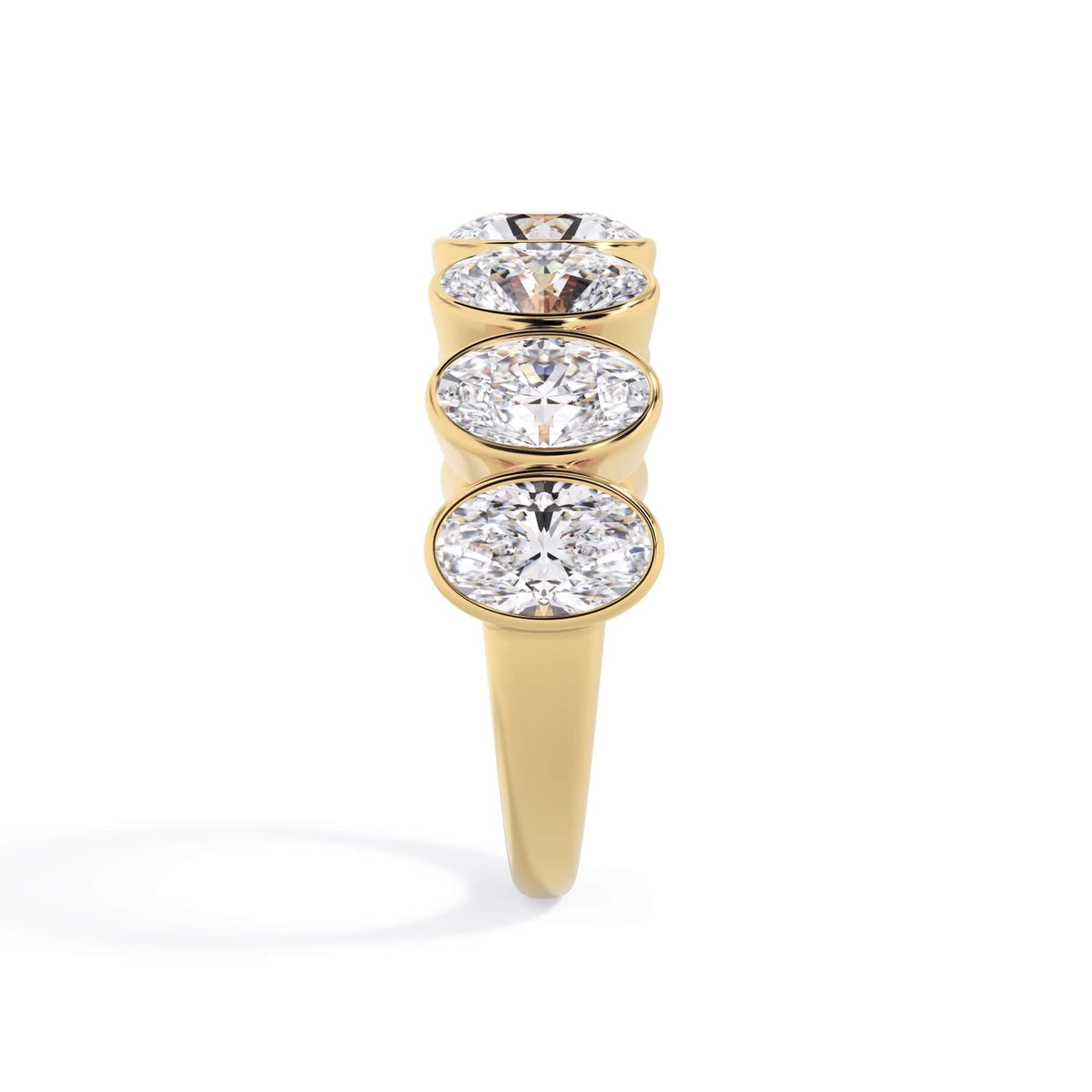 A picture of a seven stone diamond wedding ring with oval shaped diamonds that are bezel set in yellow gold on a white background with a side profile view.