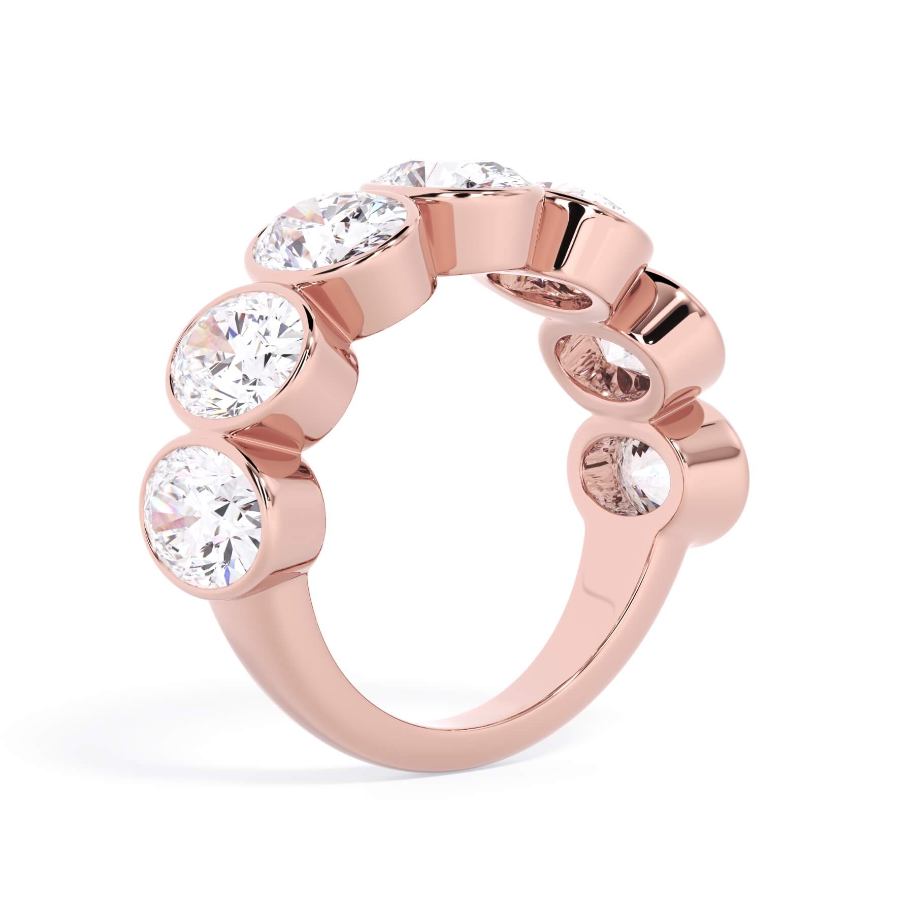 A picture of a seven stone diamond wedding ring with oval shaped diamonds that are bezel set in rose gold on a white background with a slightly angled, through the finger view.