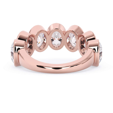 A picture of a seven stone diamond wedding ring with oval shaped diamonds that are bezel set in rose gold on a white background with a view of the underside of the ring.