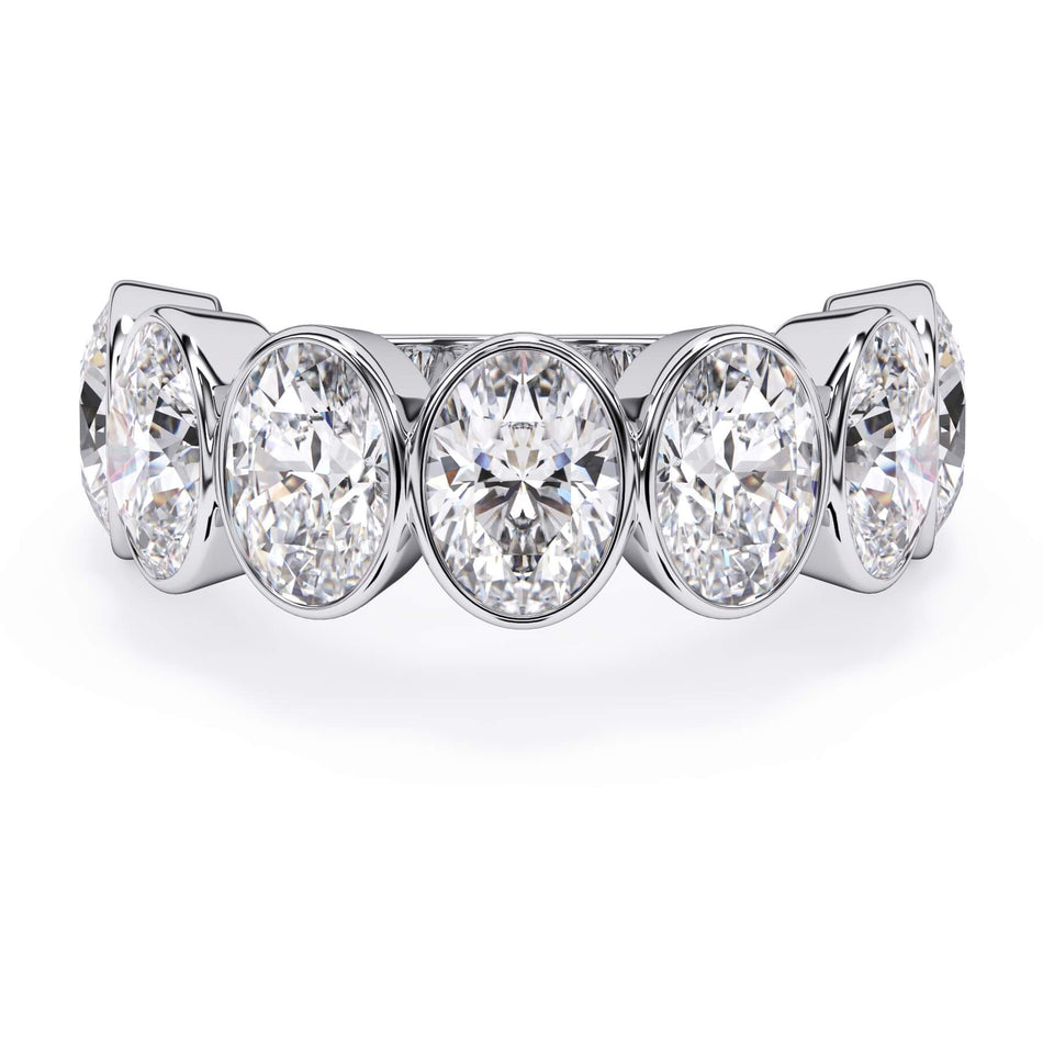 A picture of a seven stone diamond wedding ring with oval shaped diamonds that are bezel set in white gold or platinum on a white background with the ring facing forward, lying down.