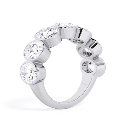 A picture of a seven stone diamond wedding ring with oval shaped diamonds that are bezel set in white gold or platinum on a white background with a slightly angled, through the finger view.