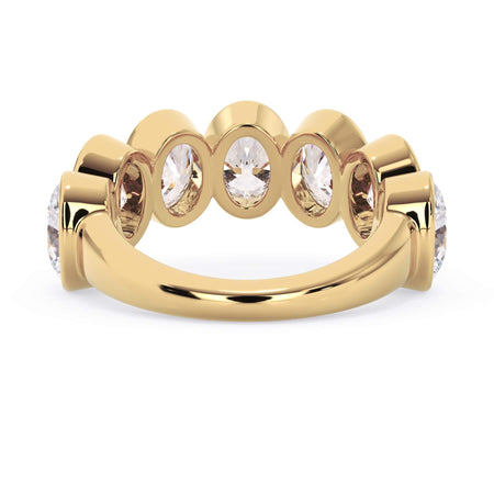 A picture of a seven stone diamond wedding ring with oval shaped diamonds that are bezel set in yellow gold on a white background with a view of the underside of the ring.