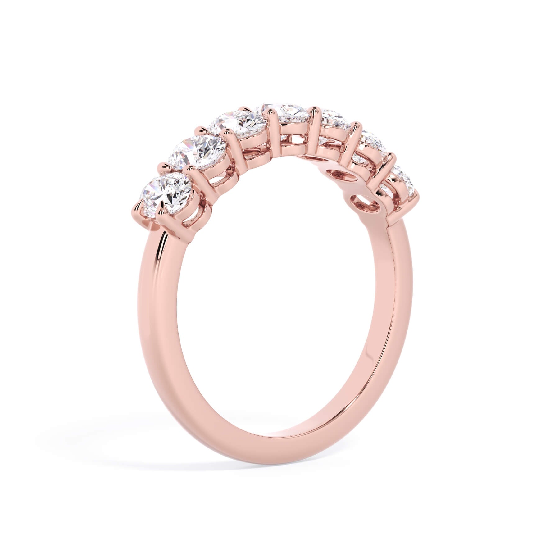 A picture of a seven stone diamond wedding ring with oval shaped diamonds that are shared prong set in rose gold on a white background with a slightly angled, through the finger view.