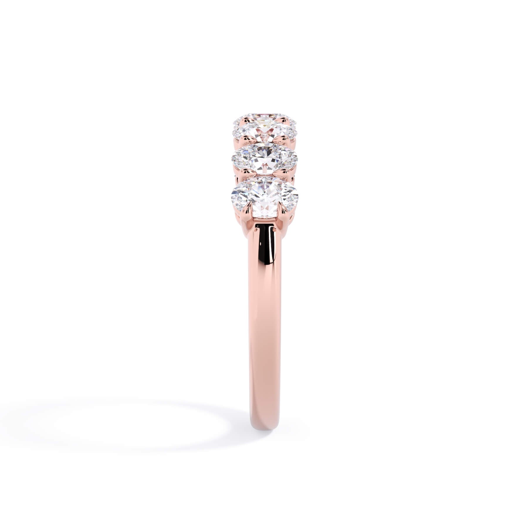 A picture of a seven stone diamond wedding ring with oval shaped diamonds that are shared prong set in rose gold on a white background with a side profile view.