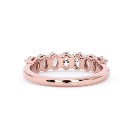 A picture of a seven stone diamond wedding ring with oval shaped diamonds that are shared prong set in rose gold on a white background with a view of the underside of the ring.