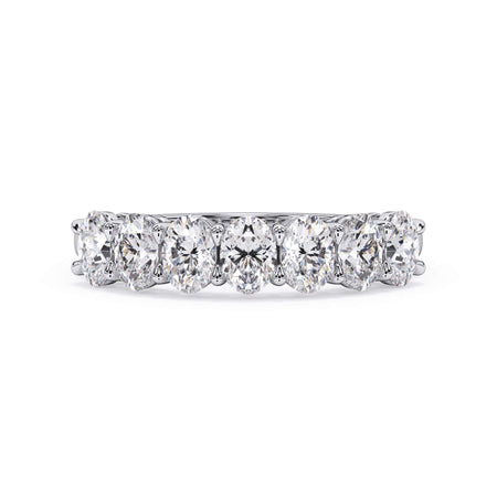 A picture of a seven stone diamond wedding ring with oval shaped diamonds that are shared prong set in white gold or platinum on a white background with the ring facing forward, lying down.