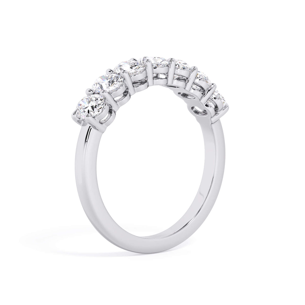 A picture of a seven stone diamond wedding ring with oval shaped diamonds that are shared prong set in white gold or platinum on a white background with a slightly angled, through the finger view.