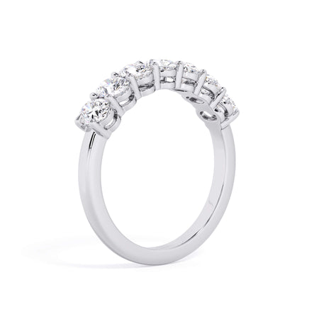 A picture of a seven stone diamond wedding ring with oval shaped diamonds that are shared prong set in white gold or platinum on a white background with a slightly angled, through the finger view.