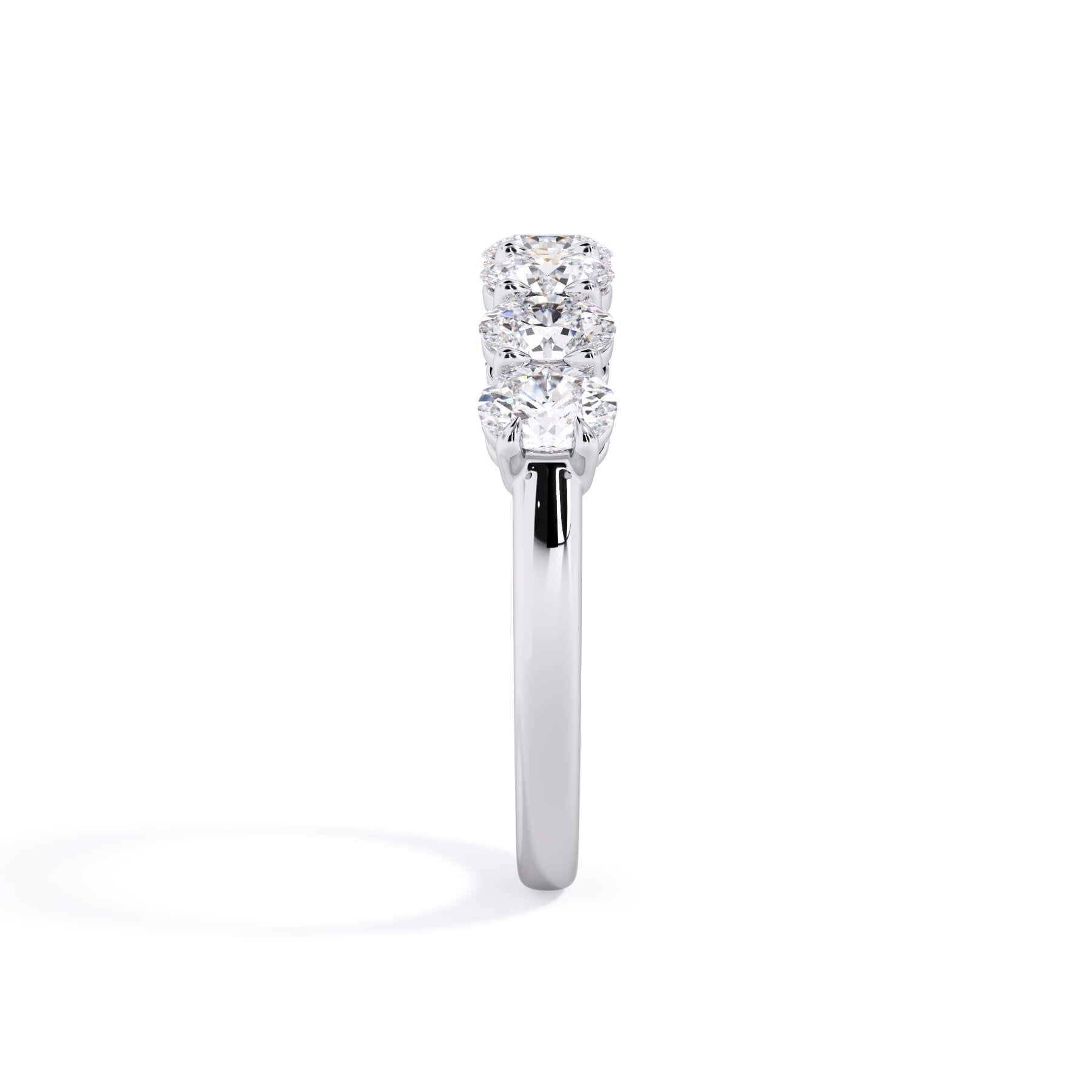 A picture of a seven stone diamond wedding ring with oval shaped diamonds that are shared prong set in white gold or platinum on a white background with a side profile view.