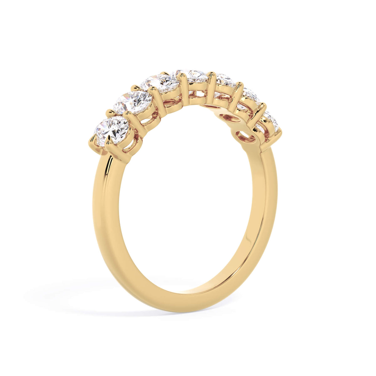 A picture of a seven stone diamond wedding ring with oval shaped diamonds that are shared prong set in yellow gold on a white background with a slightly angled, through the finger view.