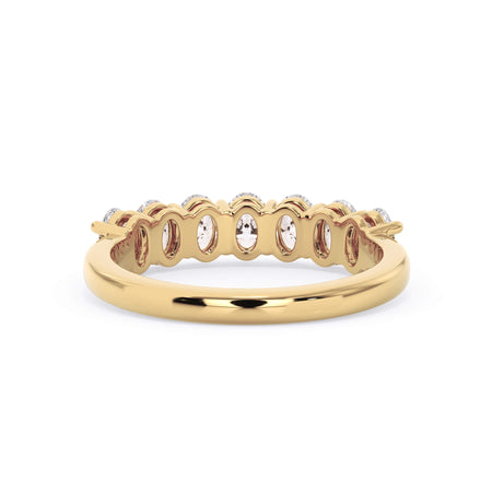 A picture of a seven stone diamond wedding ring with oval shaped diamonds that are shared prong set in yellow gold on a white background with a view of the underside of the ring.