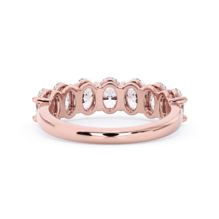 A picture of a seven stone diamond wedding ring with oval shaped diamonds that are shared prong set in rose gold on a white background with a view of the underside of the ring.