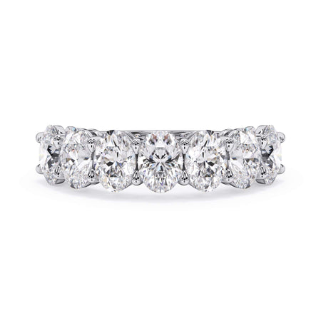 A picture of a seven stone diamond wedding ring with oval shaped diamonds that are shared prong set in white gold or platinum on a white background with the ring facing forward, lying down.