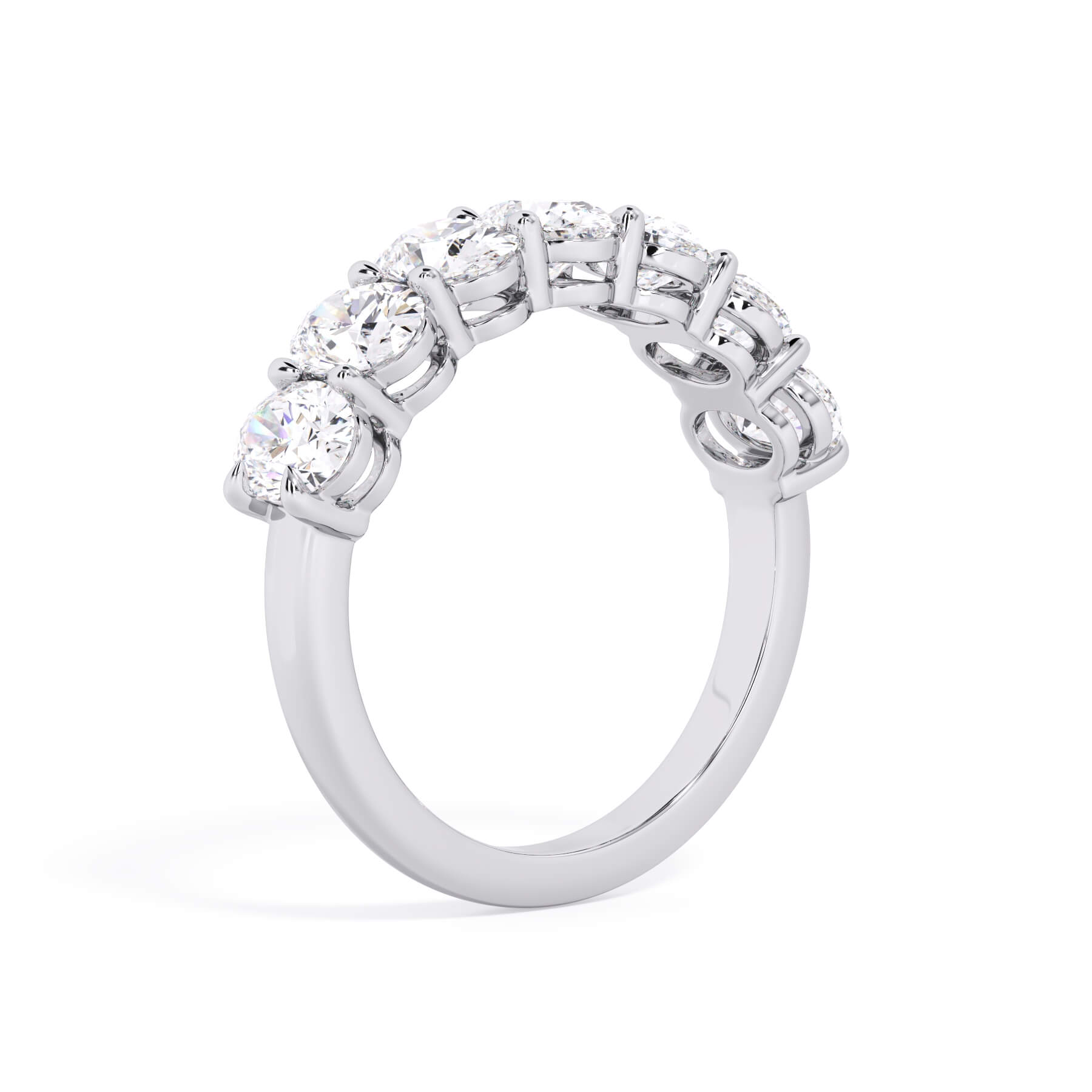 A picture of a seven stone diamond wedding ring with oval shaped diamonds that are shared prong set in white gold or platinum on a white background with a slightly angled, through the finger view.