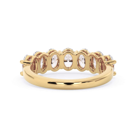 A picture of a seven stone diamond wedding ring with oval shaped diamonds that are shared prong set in yellow gold on a white background with a view of the underside of the ring.