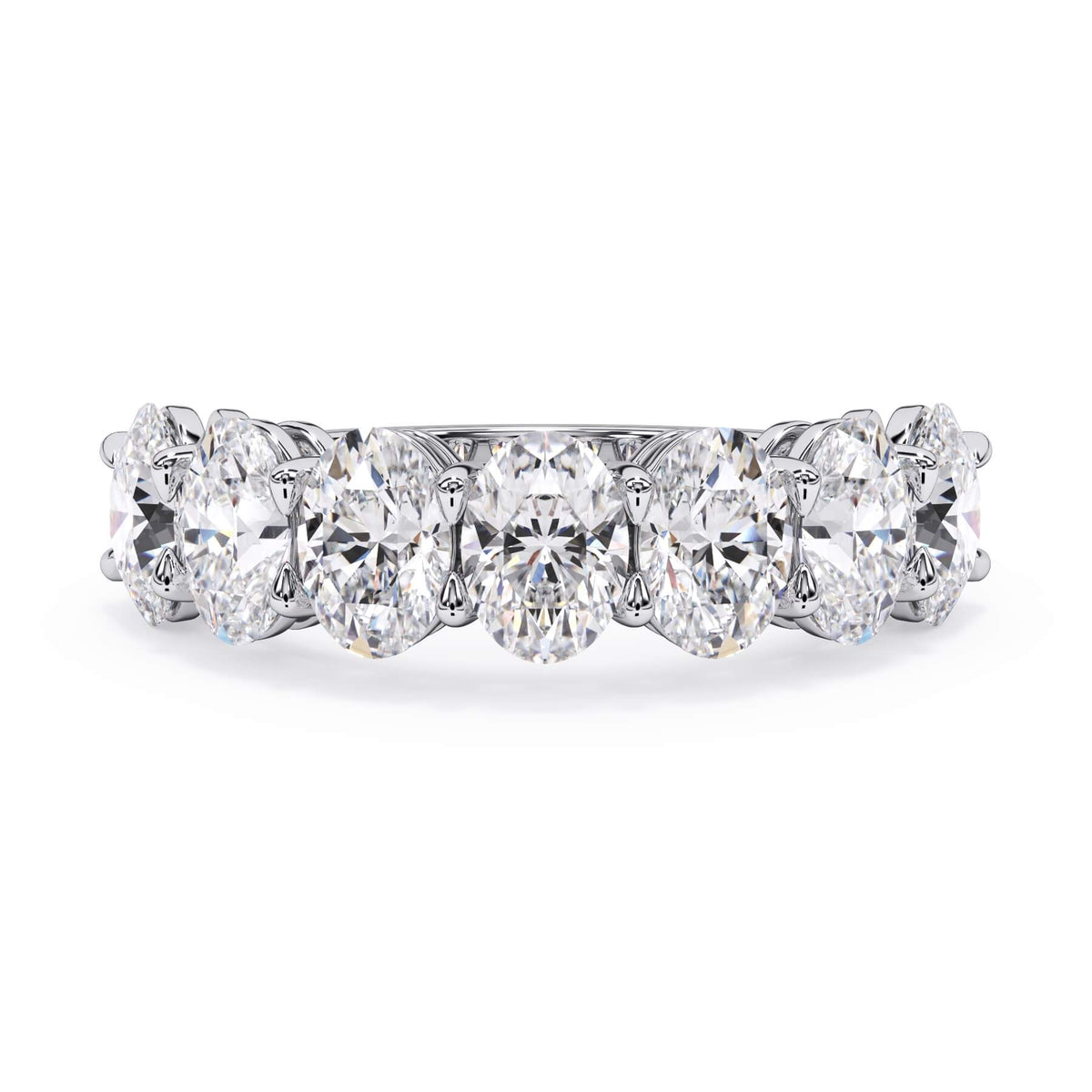 A picture of a seven stone diamond wedding ring with oval shaped diamonds that are shared prong set in white gold or platinum on a white background with the ring facing forward, lying down.