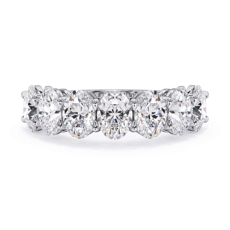 A picture of a seven stone diamond wedding ring with oval shaped diamonds that are shared prong set in white gold or platinum on a white background with the ring facing forward, lying down.