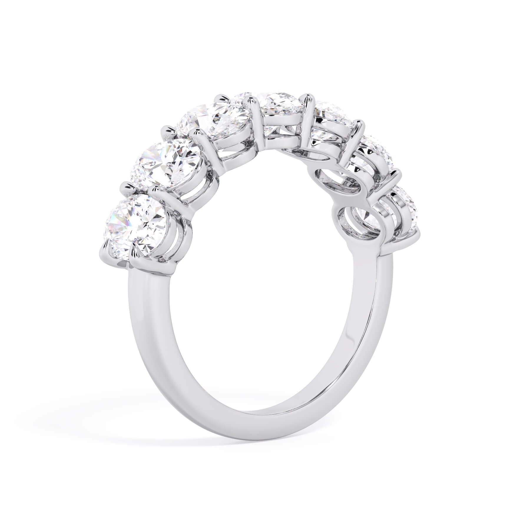 A picture of a seven stone diamond wedding ring with oval shaped diamonds that are shared prong set in white gold or platinum on a white background with a slightly angled, through the finger view.