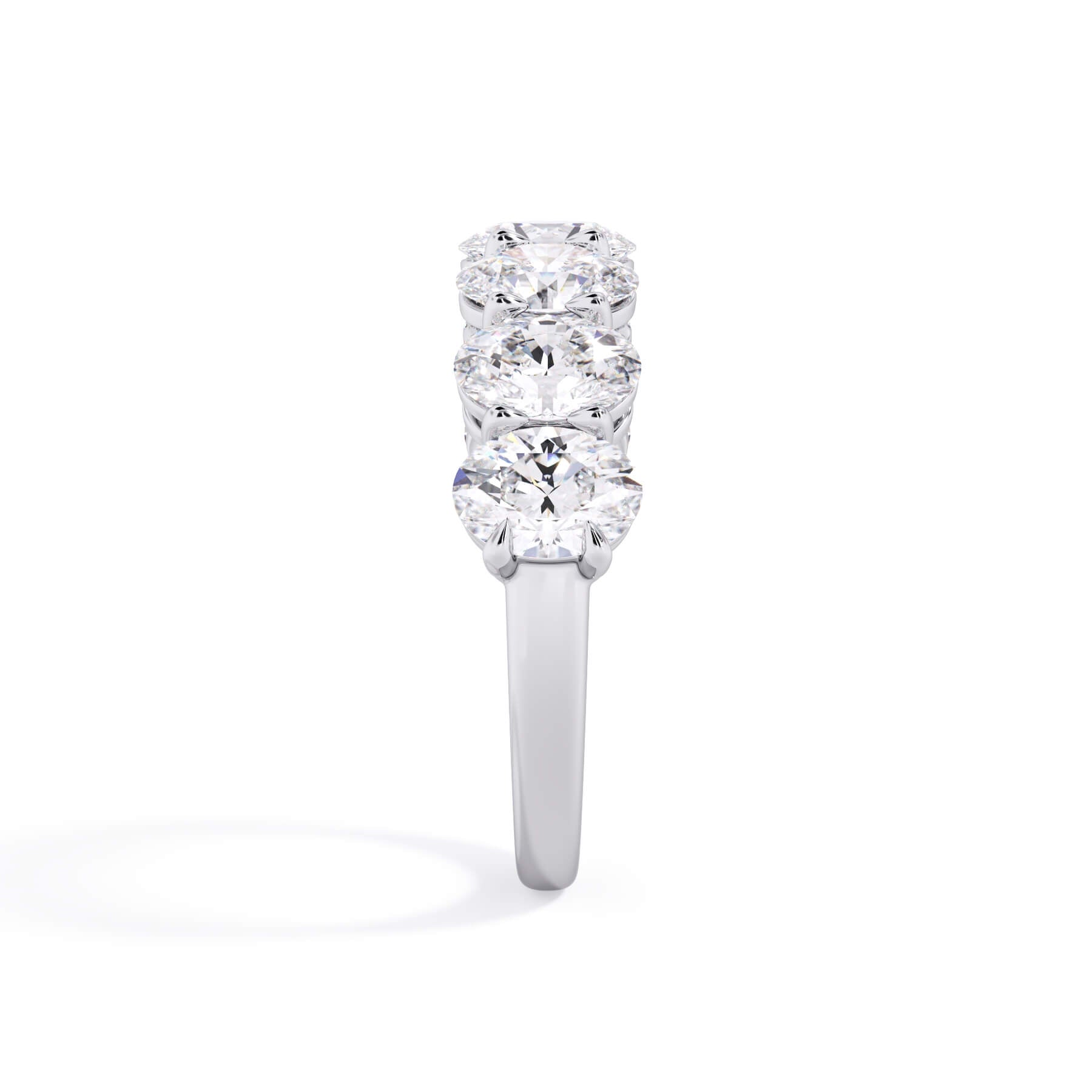 A picture of a seven stone diamond wedding ring with oval shaped diamonds that are shared prong set in white gold or platinum on a white background with a side profile view.