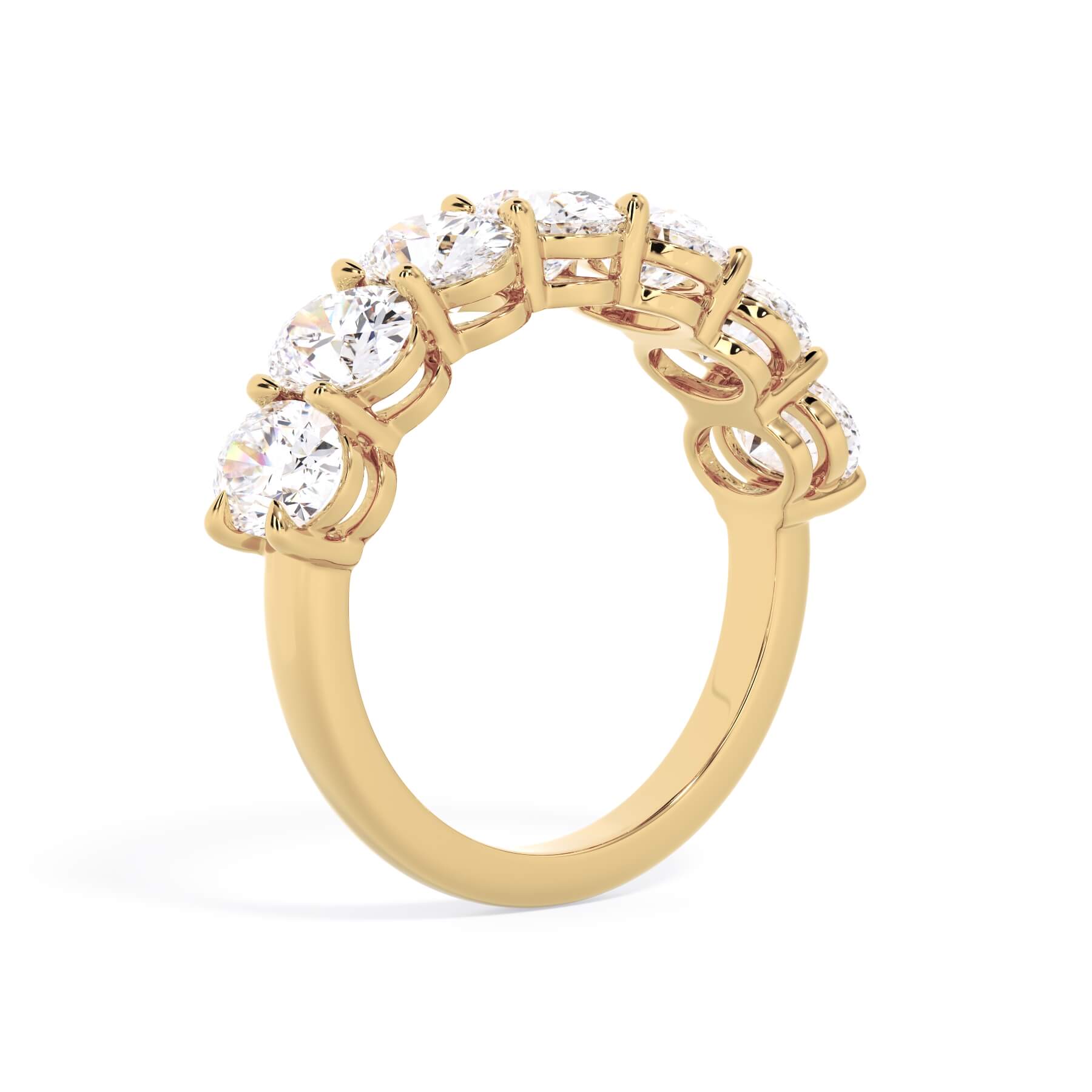 A picture of a seven stone diamond wedding ring with oval shaped diamonds that are shared prong set in yellow gold on a white background with a slightly angled, through the finger view.