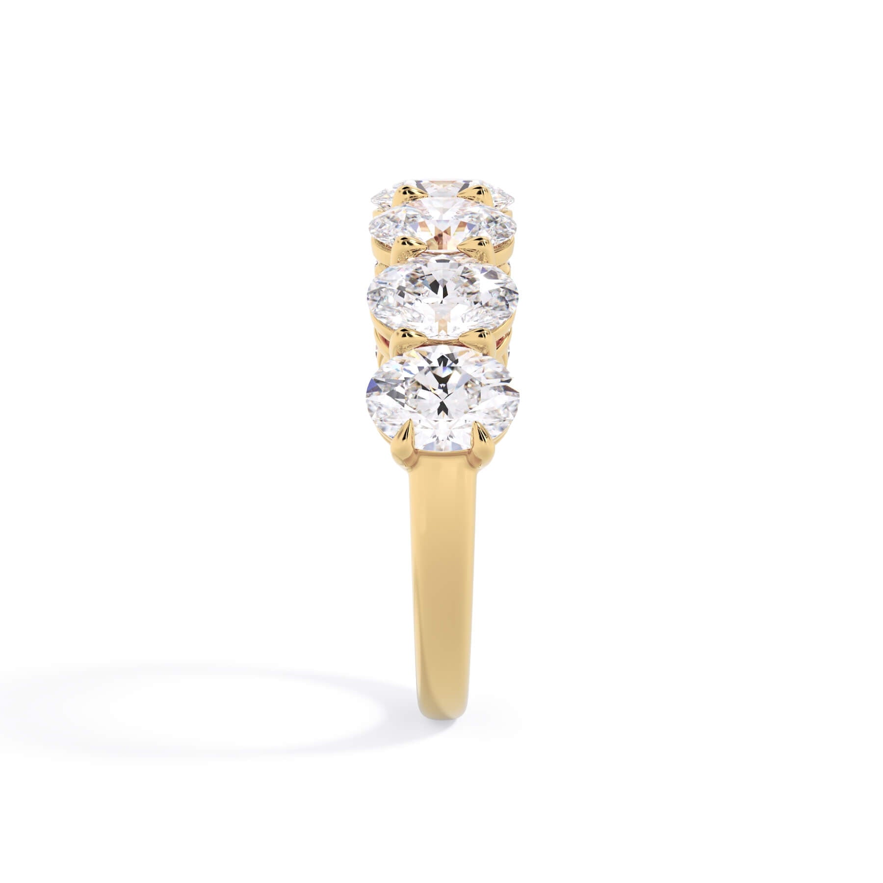 A picture of a seven stone diamond wedding ring with oval shaped diamonds that are shared prong set in yellow gold on a white background with a side profile view.