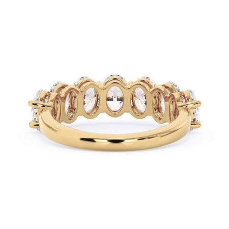 A picture of a seven stone diamond wedding ring with oval shaped diamonds that are shared prong set in yellow gold on a white background with a view of the underside of the ring.