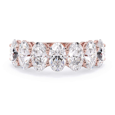 A picture of a seven stone diamond wedding ring with oval shaped diamonds that are shared prong set in rose gold on a white background with the ring facing forward, lying down.