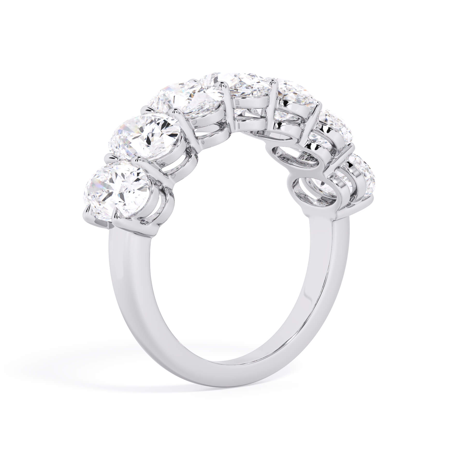 A picture of a seven stone diamond wedding ring with oval shaped diamonds that are shared prong set in white gold or platinum on a white background with a slightly angled, through the finger view.