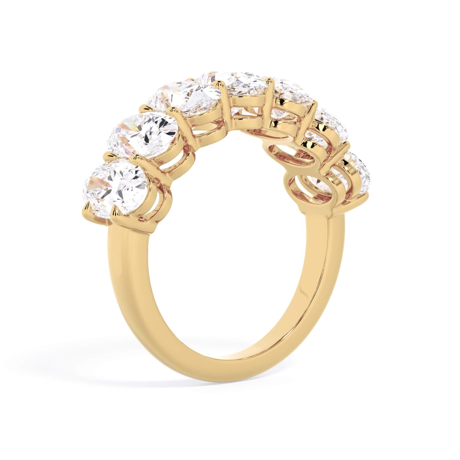 A picture of a seven stone diamond wedding ring with oval shaped diamonds that are shared prong set in yellow gold on a white background with a slightly angled, through the finger view.