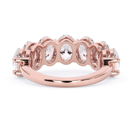 A picture of a seven stone diamond wedding ring with oval shaped diamonds that are shared prong set in rose gold on a white background with a view of the underside of the ring.