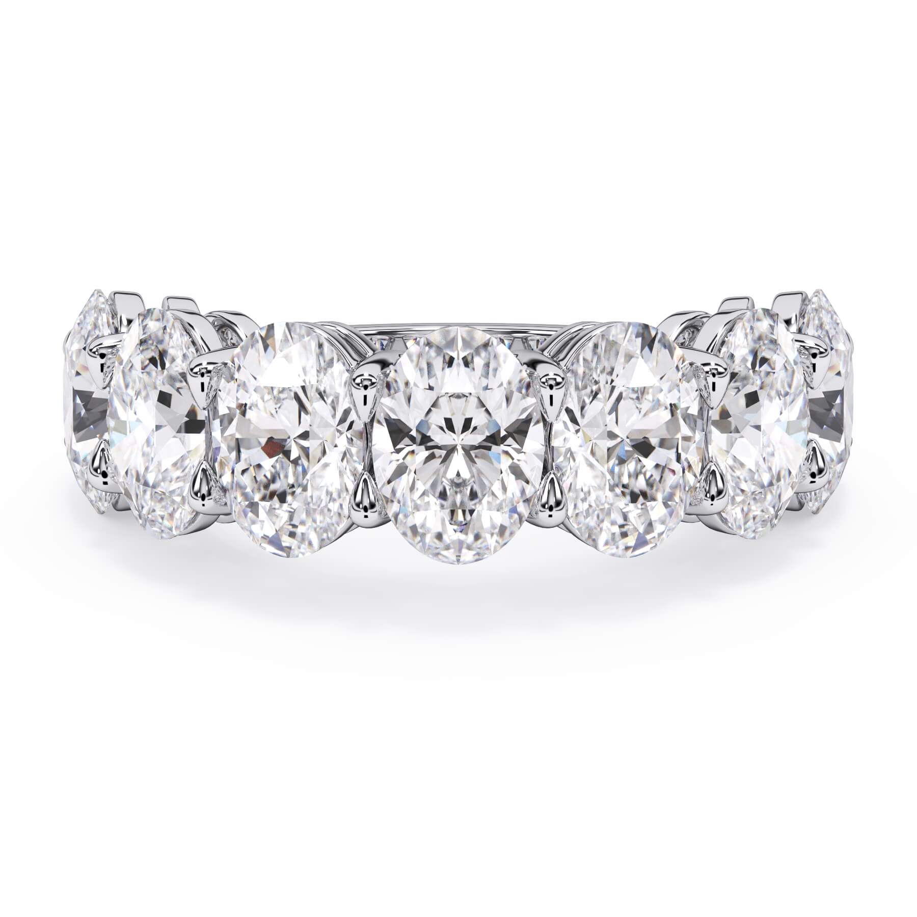 A picture of a seven stone diamond wedding ring with oval shaped diamonds that are shared prong set in white gold or platinum on a white background with the ring facing forward, lying down.