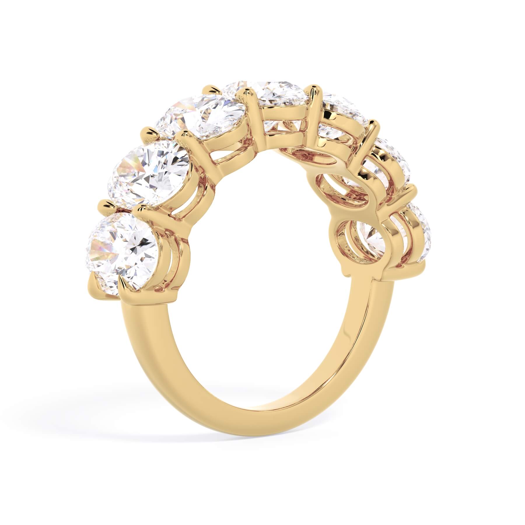 A picture of a seven stone diamond wedding ring with oval shaped diamonds that are shared prong set in yellow gold on a white background with a slightly angled, through the finger view.