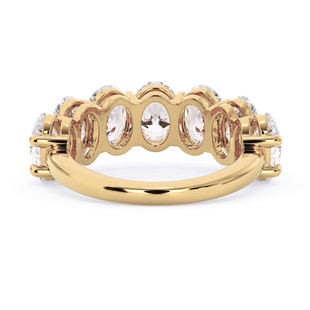 A picture of a seven stone diamond wedding ring with oval shaped diamonds that are shared prong set in yellow gold on a white background with a view of the underside of the ring.