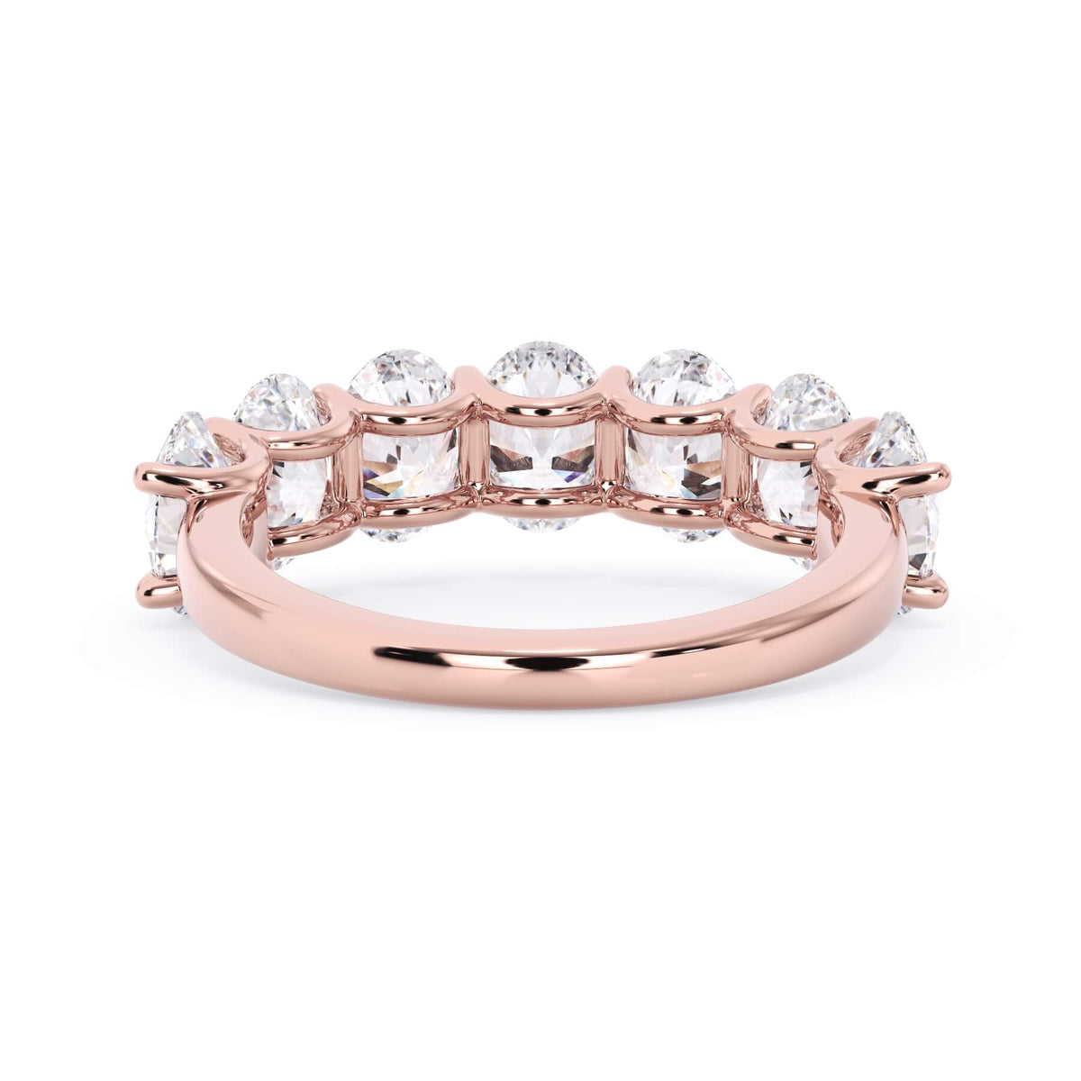 A picture of a seven stone diamond wedding ring with oval shaped diamonds that are U prong set in rose gold on a white background with a view of the underside of the ring.