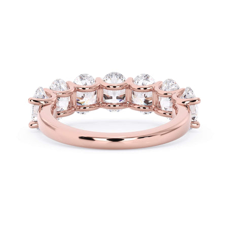 A picture of a seven stone diamond wedding ring with oval shaped diamonds that are U prong set in rose gold on a white background with a view of the underside of the ring.