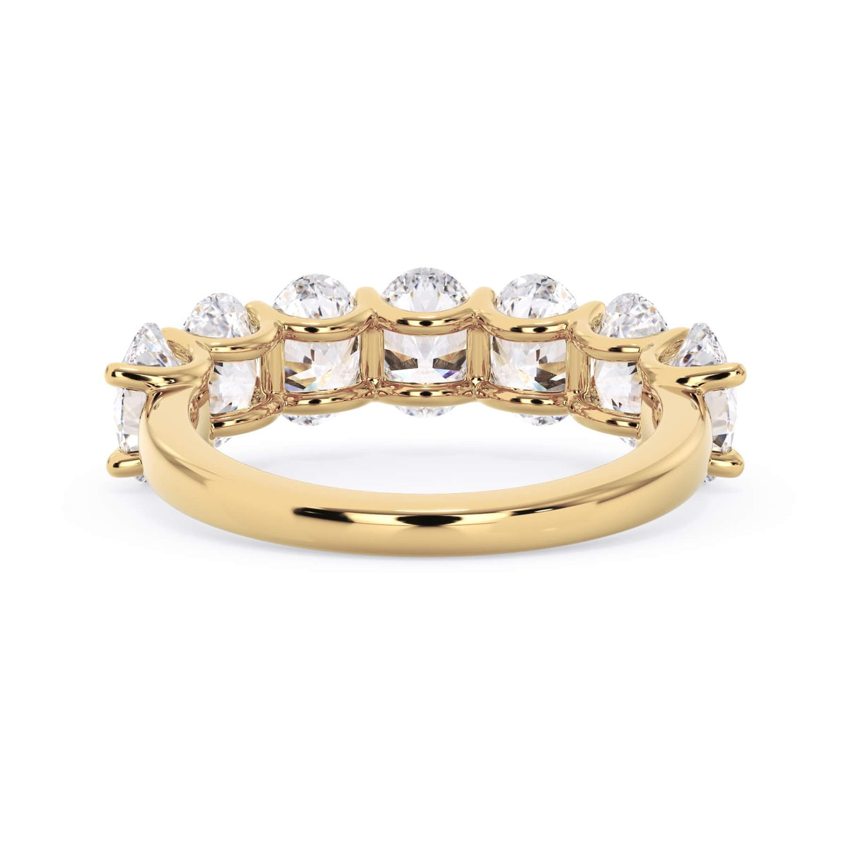 A picture of a seven stone diamond wedding ring with oval shaped diamonds that are U prong set in yellow gold on a white background with a view of the underside of the ring.