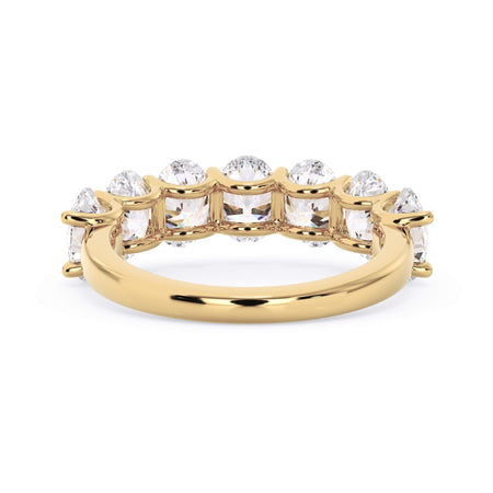A picture of a seven stone diamond wedding ring with oval shaped diamonds that are U prong set in yellow gold on a white background with a view of the underside of the ring.