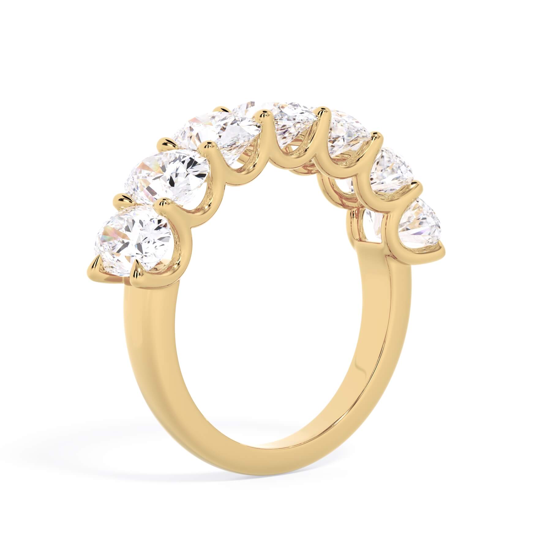 A picture of a seven stone diamond wedding ring with oval shaped diamonds that are U prong set in yellow gold on a white background with a slightly angled, through the finger view.