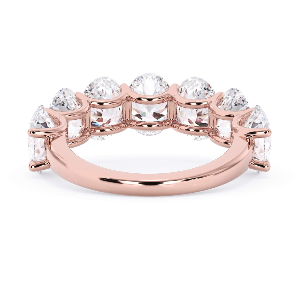 A picture of a seven stone diamond wedding ring with oval shaped diamonds that are U prong set in rose gold on a white background with a view of the underside of the ring.