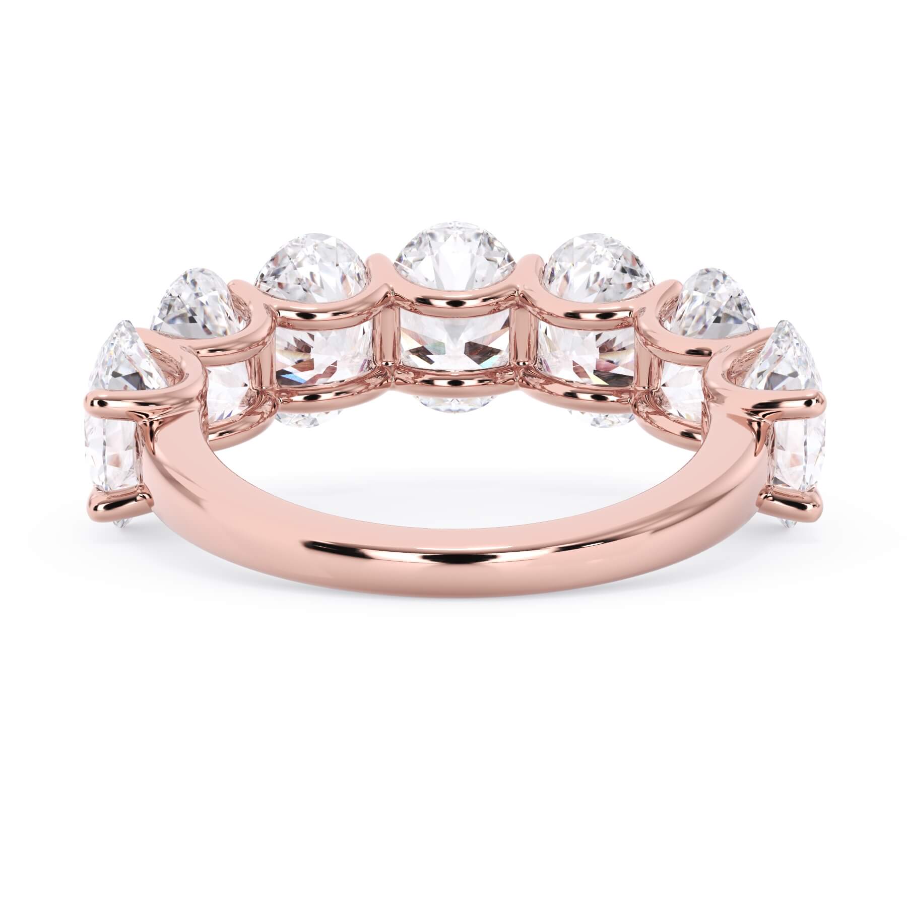 A picture of a seven stone diamond wedding ring with oval shaped diamonds that are U prong set in rose gold on a white background with a view of the underside of the ring.